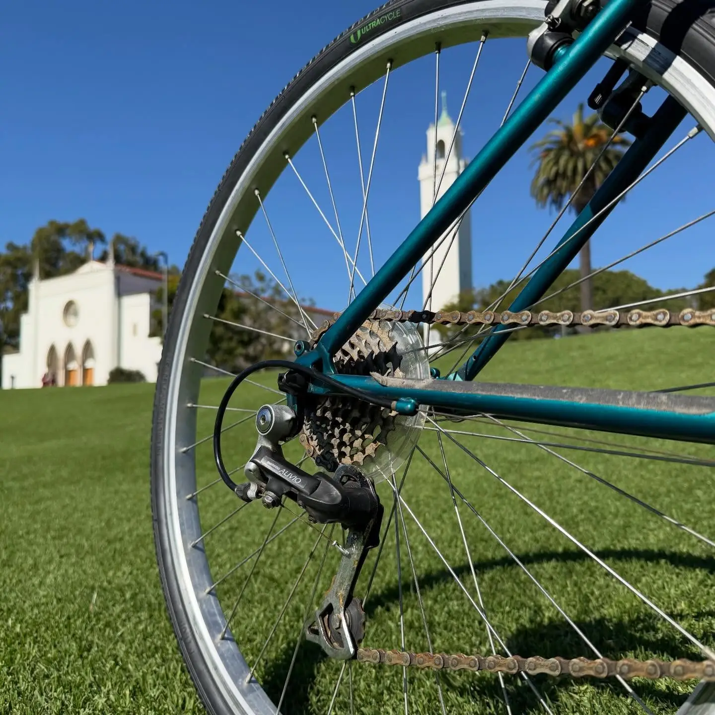 A dark green cruiser with cream tires on a dirt path, dry chaparral grasses and Los Angeles hills in the distance.
