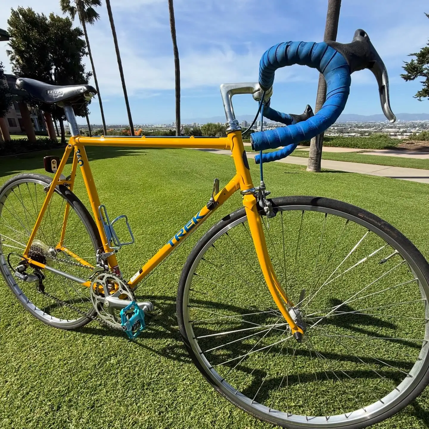 A clean side profile of a yellow Trek mountain bike against a white stucco wall.